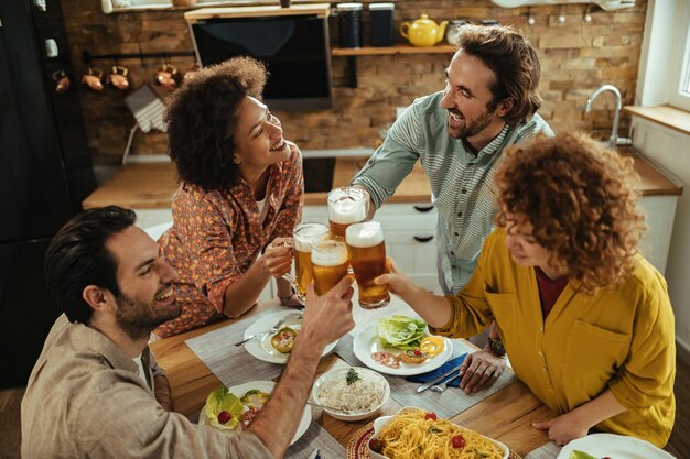 함께 점심을 먹고 식탁에서 맥주와 함께 건배하는 행복한 친구들의 높은 각도.