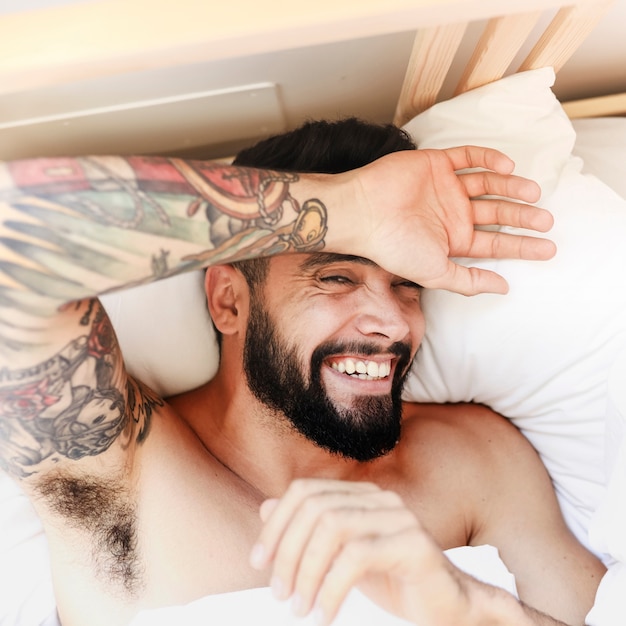 High angle view of a happy man lying on bed