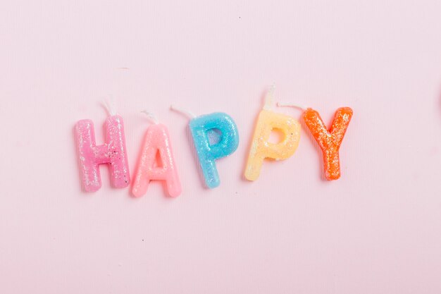 High angle view of happy word candles on pink background