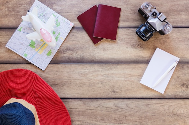 Free photo high angle view of hat; map; airplane; passport; camera; paper and pain on wooden surface