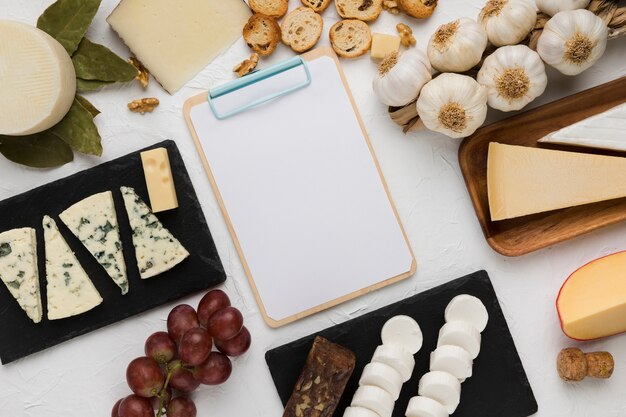 High angle view of healthy ingredient and various cheese with empty clipboard