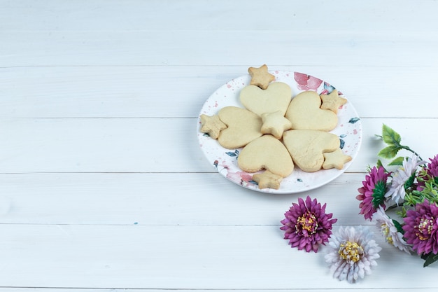 High angle view heart shaped and star cookies in white plate with flowers