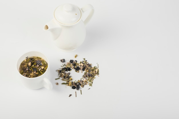 Высокий угол зрения травяной чай с чайником на белом фоне