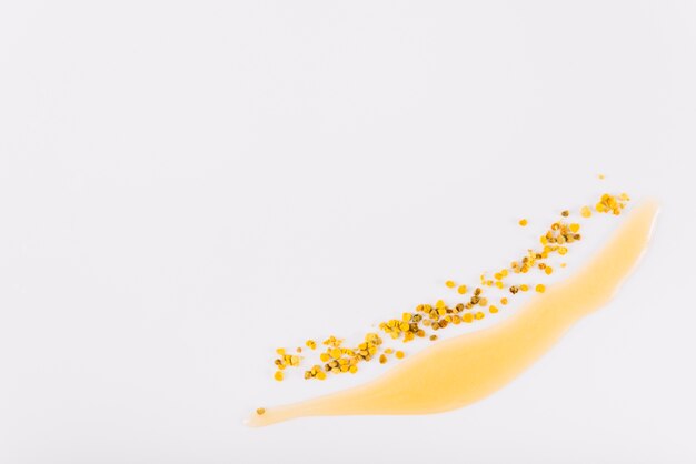 High angle view of honey and bee pollen on white backdrop