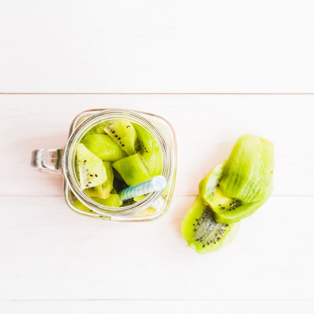 High angle view of kiwi fruit slices in jar on wooden background