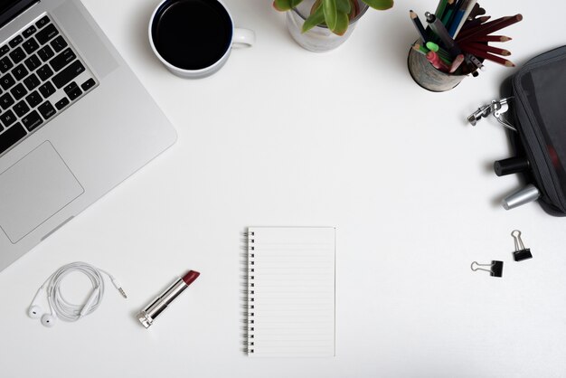 High angle view of laptop; coffee cup; makeup pouch and pencils on office desk