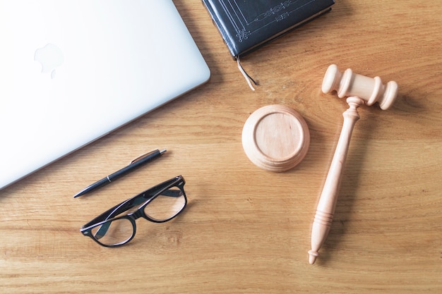 High angle view of laptop; spectacles; gavel and pen on wooden background on wooden desk