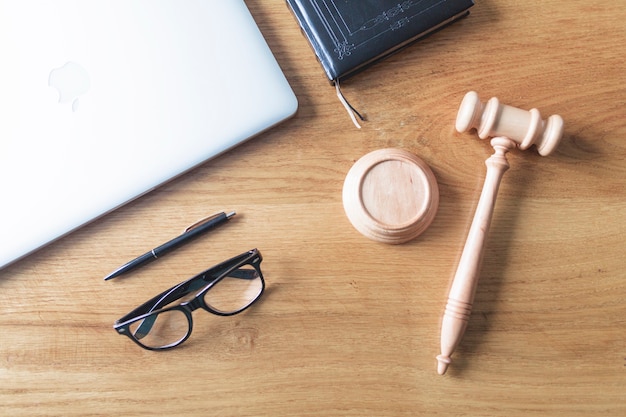 Высокий угол зрения ноутбука; очки; молоток и ручка на деревянном фоне на деревянном столе
