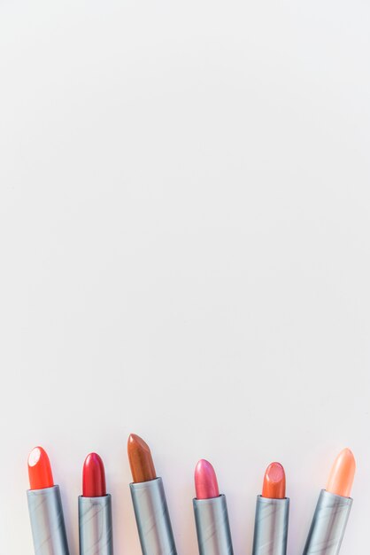High angle view of lipsticks shades on white background arranged in a row