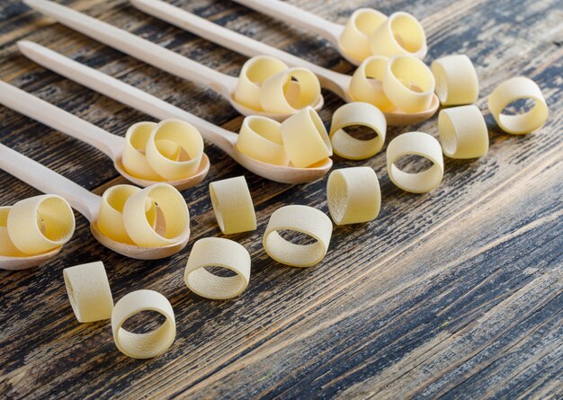 High angle view macaroni pasta in spoons on dark wooden background. horizontal