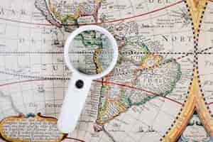 Free photo high angle view of magnifying glass on old world map