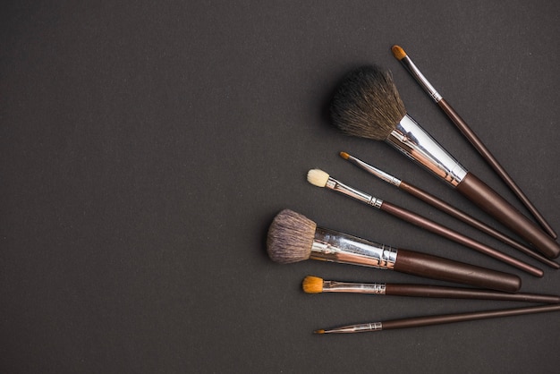 Free photo high angle view of makeup brushes on black surface