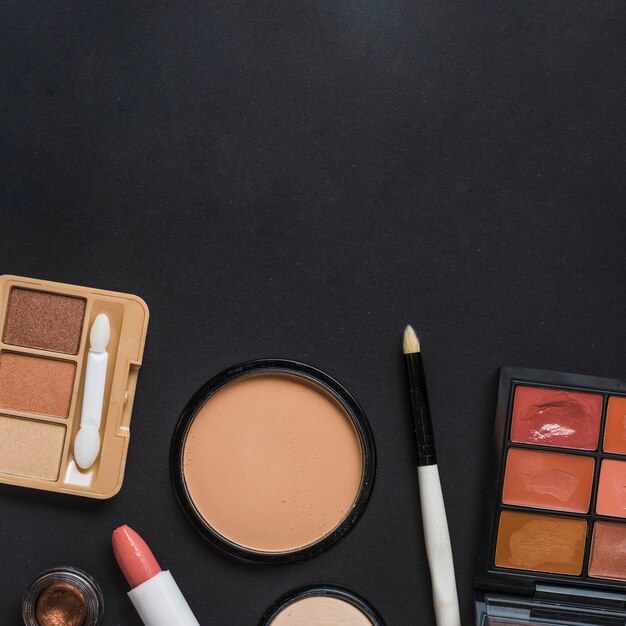 High angle view of makeup kit on black backdrop