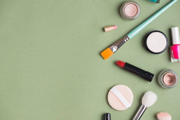 High angle view of makeup kit on green backdrop