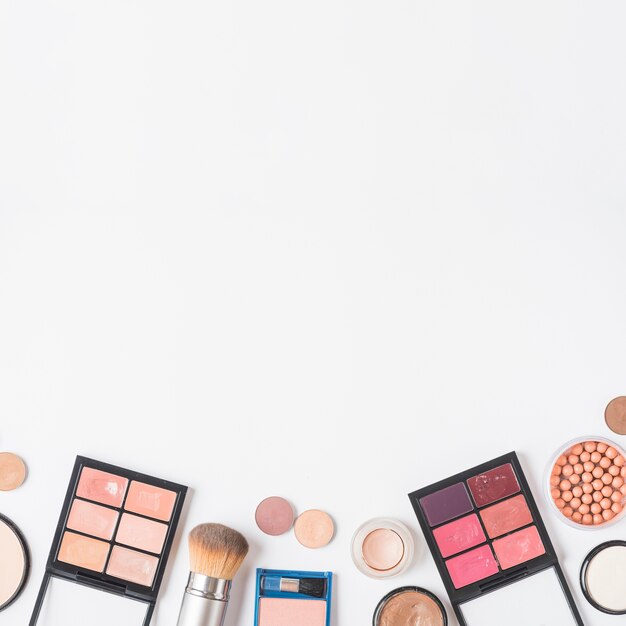 High angle view of makeup kits at the bottom of white backdrop