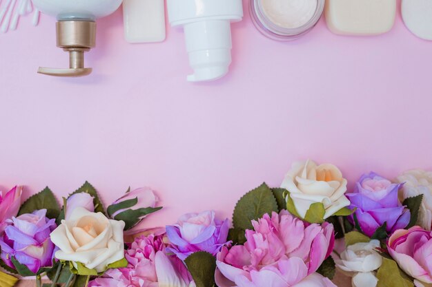 Foto gratuita vista dell'angolo alto della crema idratante e dei fiori falsi su fondo rosa