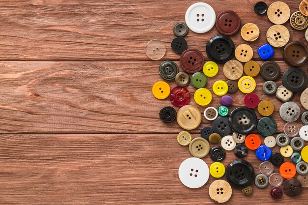 High angle view of multi colored buttons on wooden plank