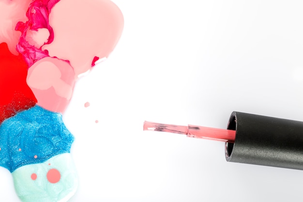 High angle view of multi colored nail polish and brush on white background