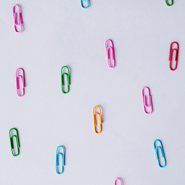 High angle view of multi colored paper clips on grey backdrop