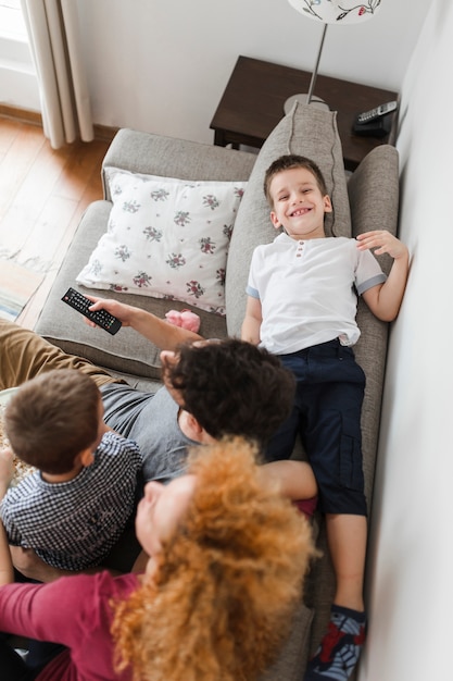 Бесплатное фото Высокий угол зрения семьи, сидя на диване, смотреть телевизор