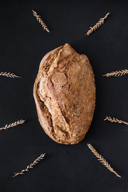 무료 사진 검은 배경에 곡물로 둘러싸인 갓 구운 빵의 높은 각도보기