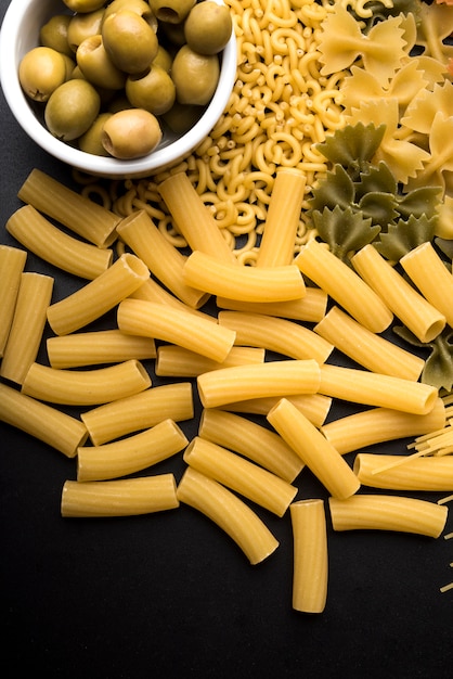 Vista dell'angolo alto di una oliva e di una pasta grezza sopra il worktop della cucina