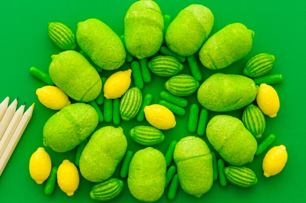 Высокий угол зрения карандашей и различных сладких конфет на зеленом фоне