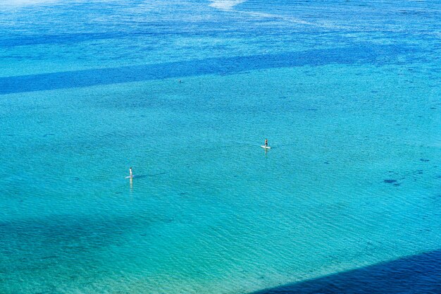 真っ青な海でサーフィンをしている人々のハイアングルビュー