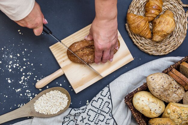 High angle view of a person's hand slicing bread on chopping board