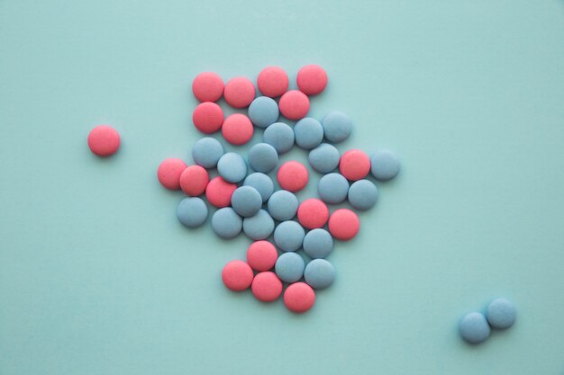 High angle view of pink and blue candies on green background