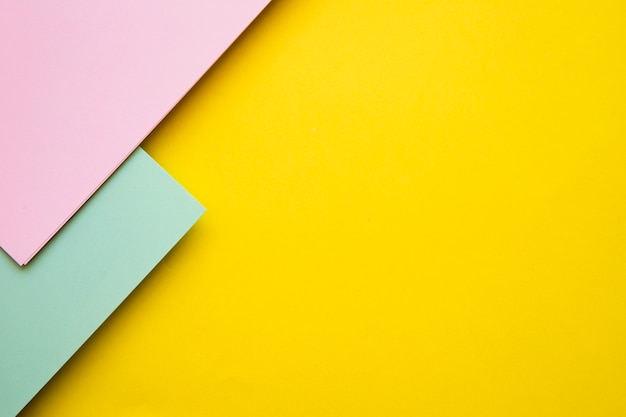 High angle view of pink and green cardboard papers on yellow backdrop