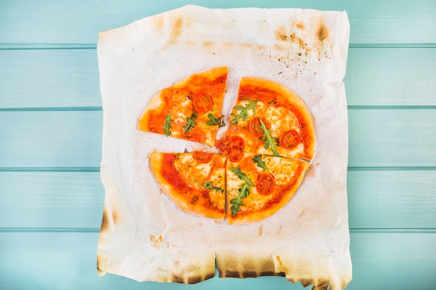 Free photo high angle view of pizza slices on burnt paper