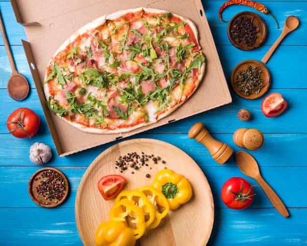 ピザのハイアングル。野菜と木の背景に対してスパイス