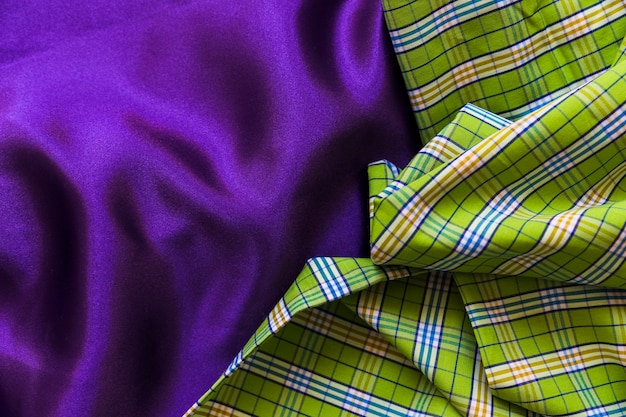 High angle view of plaid cotton cloth on plain purple textile