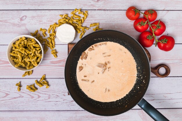 Взгляд высокого угла готовить итальянские вкусные макароны на деревянном столе