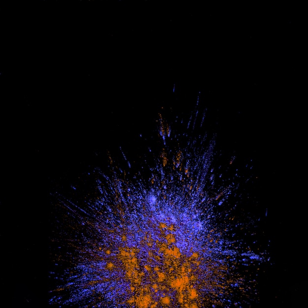 High angle view of purple and orange dust holi colored explosion over black background