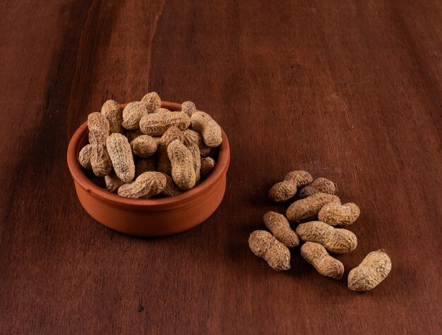 High angle view raw peanuts in bowl on wooden horizontal