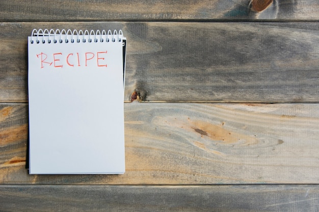 High angle view of recipe word on spiral notepad over wooden background