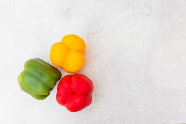 High angle view of red; green and yellow bell peppers on white background