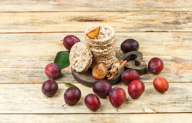 High angle view rice wafers on round cutting board with plums on wooden board table. horizontal