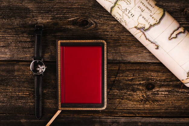 木製の表面上に巻かれた地図、日記、腕時計の高い角度のビュー