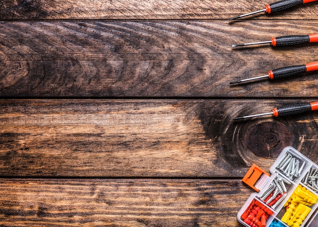 High angle view of screwdrivers and bolt kit on wooden background