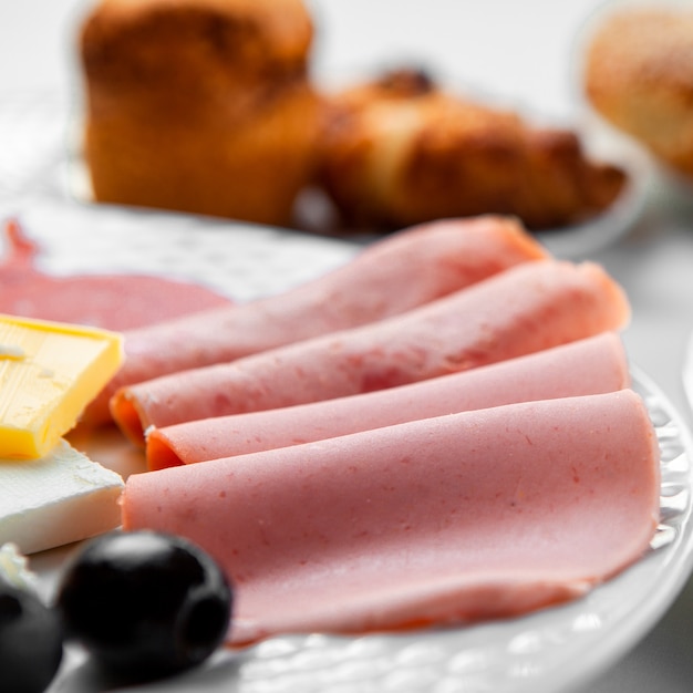 High angle view sliced sausage in plate, with pastry on table