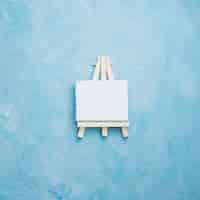 Free photo high angle view of small miniature easel on blue rough textured