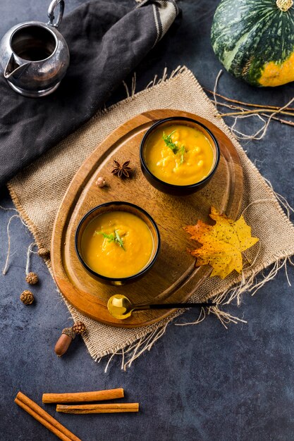 High angle view of squash soup bowls on wooden board