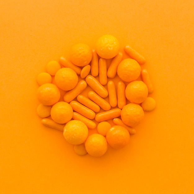 High angle view of sweet candies on orange surface