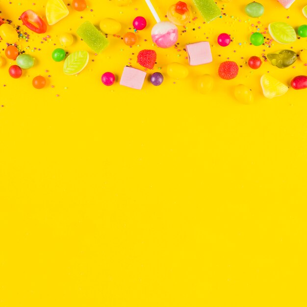 High angle view of sweet candies on yellow background