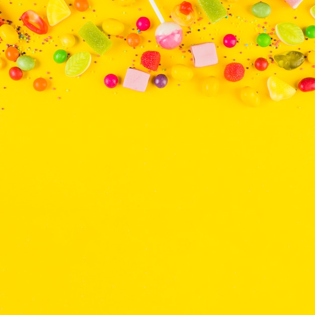 Высокий угол зрения сладкие конфеты на желтом фоне