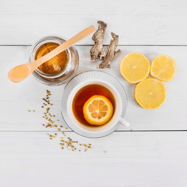 High angle view of sweet honey; lemon tea and ginger on wooden background