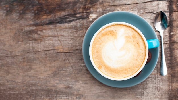 High angle view of tasty coffee with frothy foam on old wooden backdrop